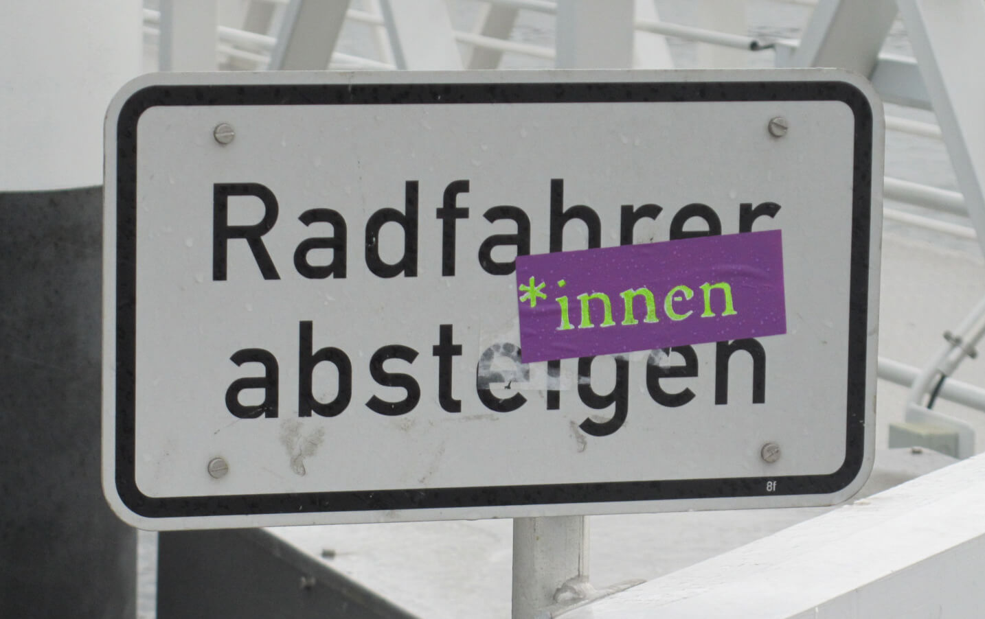 Ein Schild mit der Aufschrift Radfahrer absteigen und einem darübergeklebten *innen